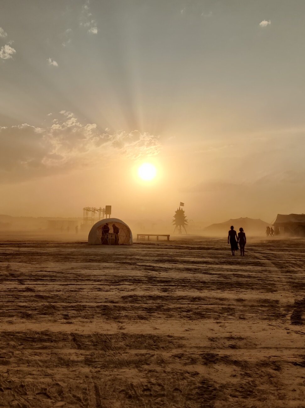 Sunrise over the Elsewhere desert town, figures silhouetted against the dust