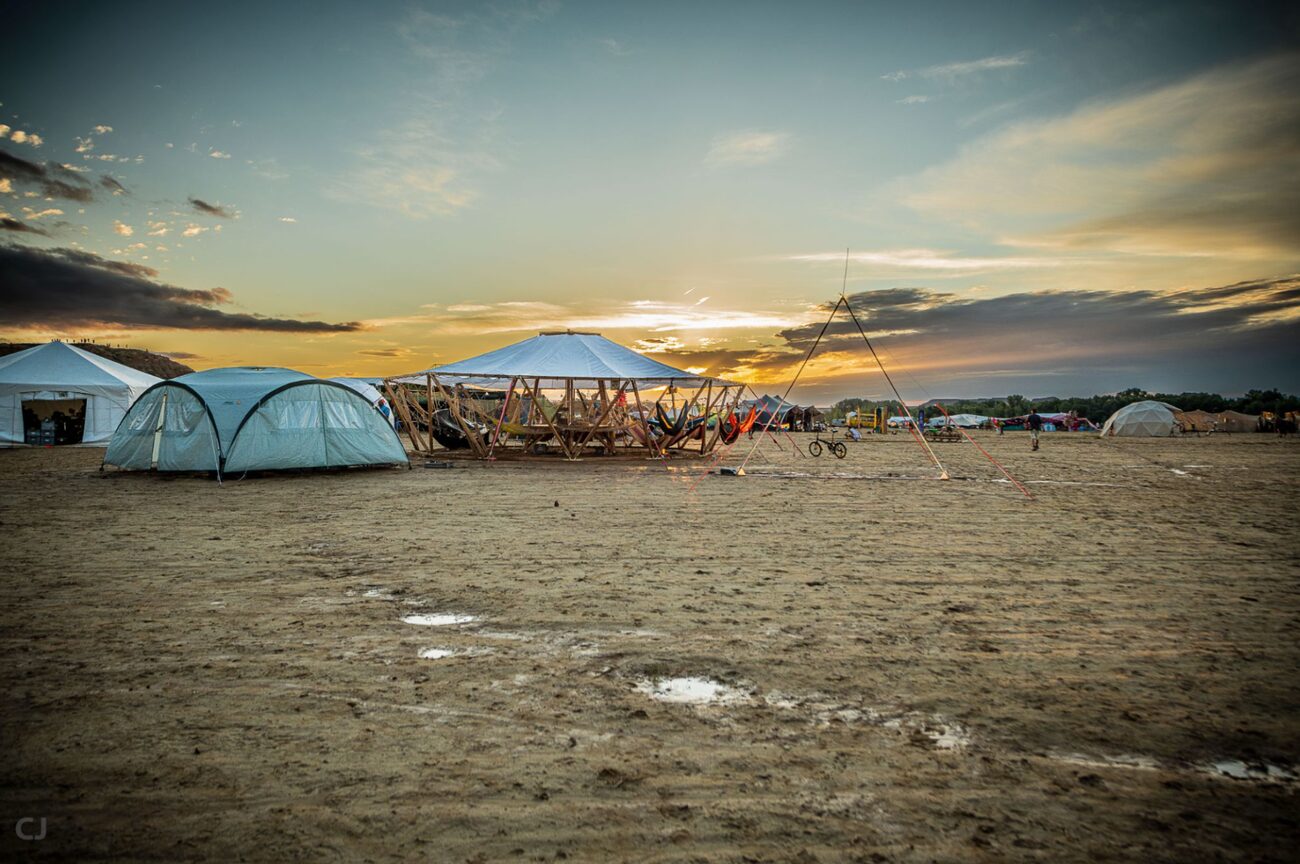 A wide view of tents across the desert at golden hour